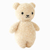 The Cuddle + Kind Baby Bouclé Bear - Honey is a soft, light brown plush teddy bear with small black eyes, a black nose, and a simple stitched mouth, standing upright against a plain white background.