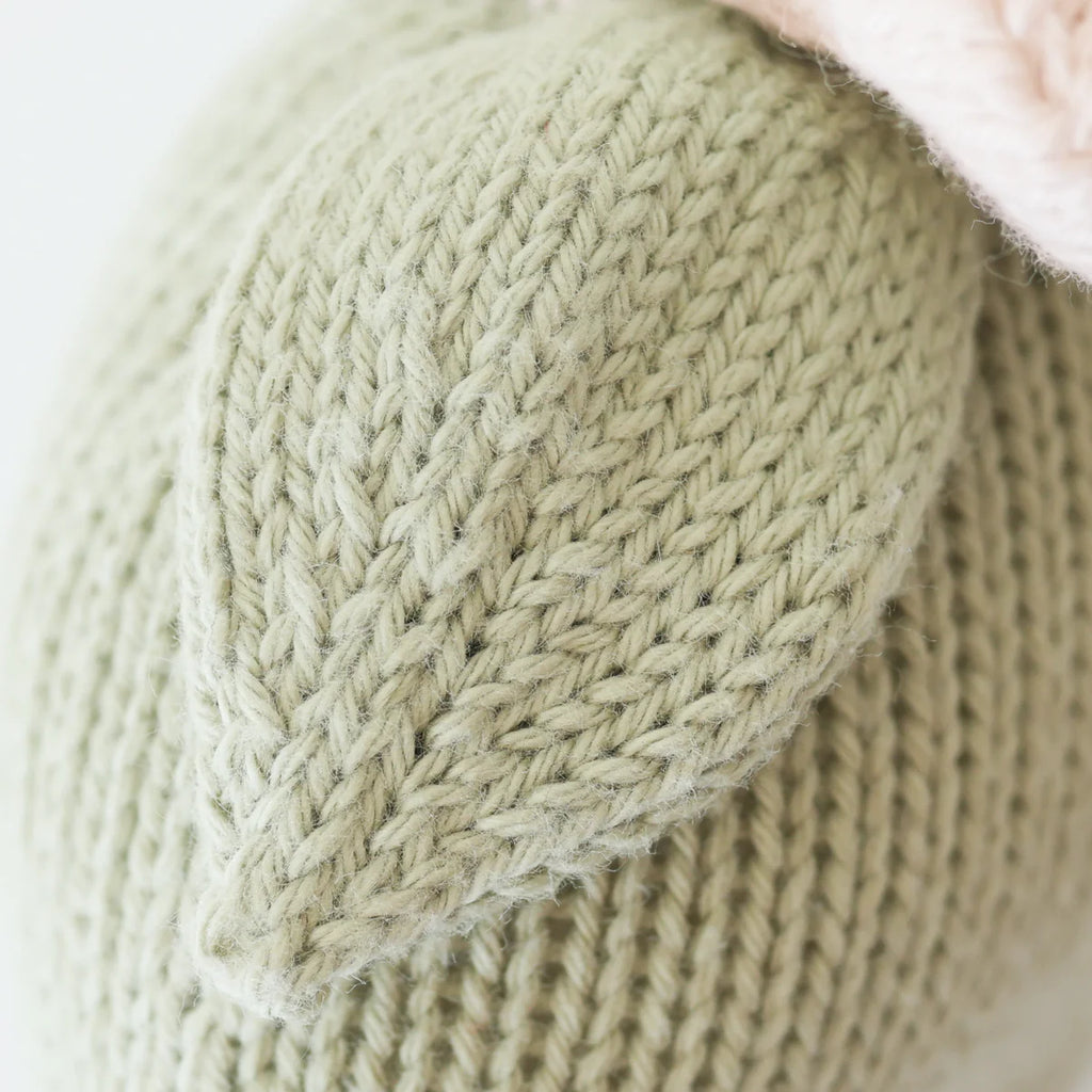 Close-up of Cuddle + Kind Baby Daisy - Blush Pink, featuring soft knitted blush pink yarn in a leaf-like shape, highlighting the detailed stitch pattern.