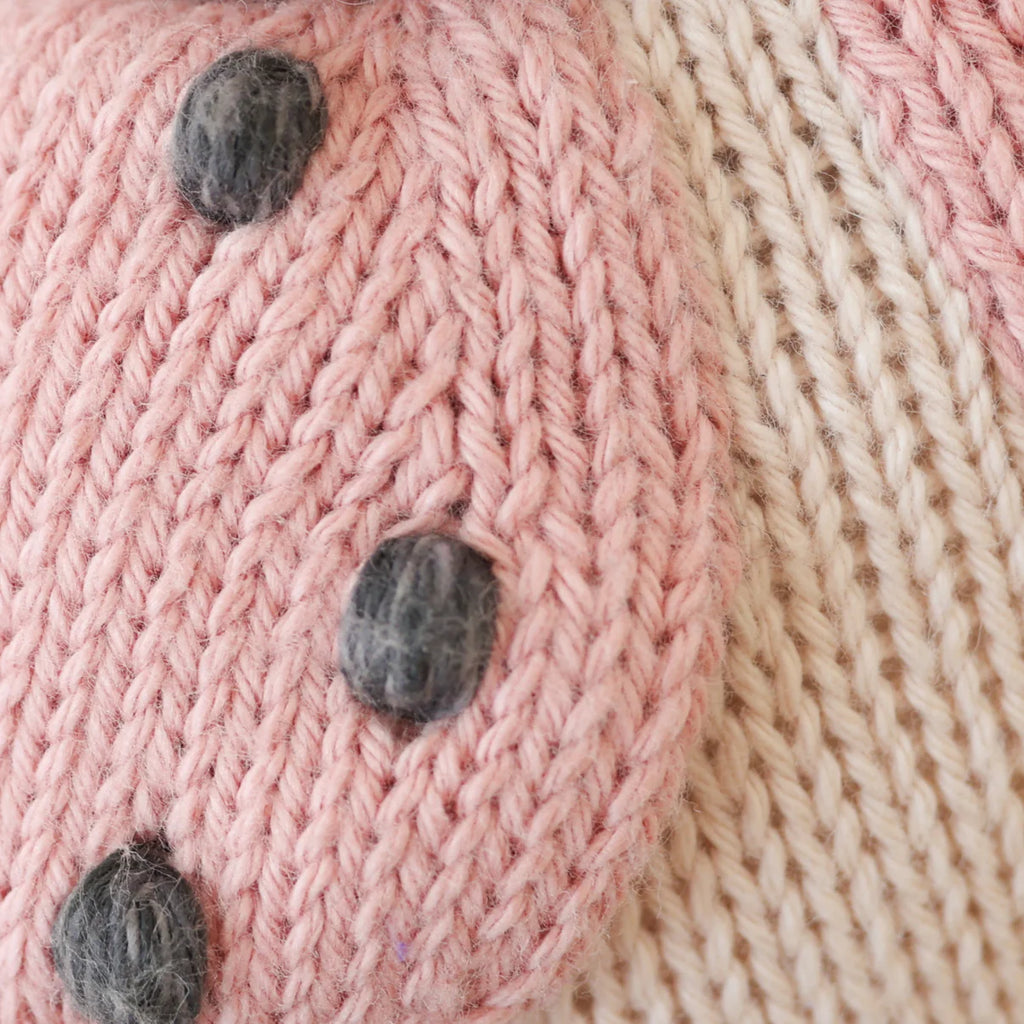 Close-up of the Cuddle + Kind Baby Ladybug's knitted fabric made from natural Peruvian cotton yarn in light pink and cream, featuring dark gray spots on the pink section with clearly visible stitch texture.