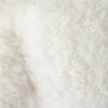 Close-up of the soft, curly textured fibers of the Cuddle + Kind Baby Bouclé Bear - Ivory, showcasing its cozy off-white plush reminiscent of collectible toys made from Peruvian alpaca yarn.