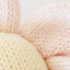 Close-up of Cuddle + Kind Baby Daisy - Blush Pink, featuring soft, fair trade, hand-knit fabric in cream and blush from natural Peruvian cotton yarn—cozy textured threads evoke lovingly crafted baby animals.