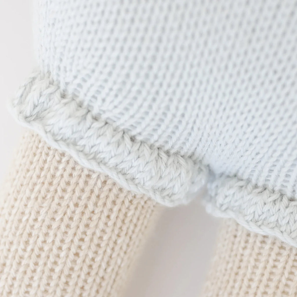 Close-up of Cuddle + Kind Beatrice The Mouse - Periwinkle, featuring textured cream and light blue knits separated by a decorative edge, showcasing the intricate stitching and soft materials used in this sustainable, fair trade handmade doll.