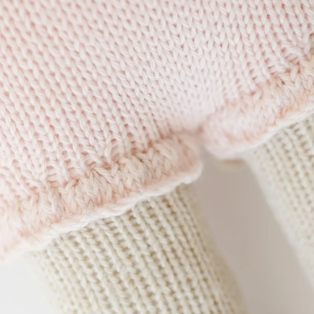 Close-up of Cuddle + Kind Beatrice The Mouse - Blush, showing her handmade soft pink cotton skirt with scalloped edges and cream-colored legs.