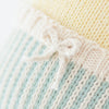 Close-up of the Cuddle + Kind Duckling, featuring soft, hand-knit 100% cotton fabric in pale yellow, blue, and white. A small white bow at the seam highlights its delicate stitching and cozy texture.