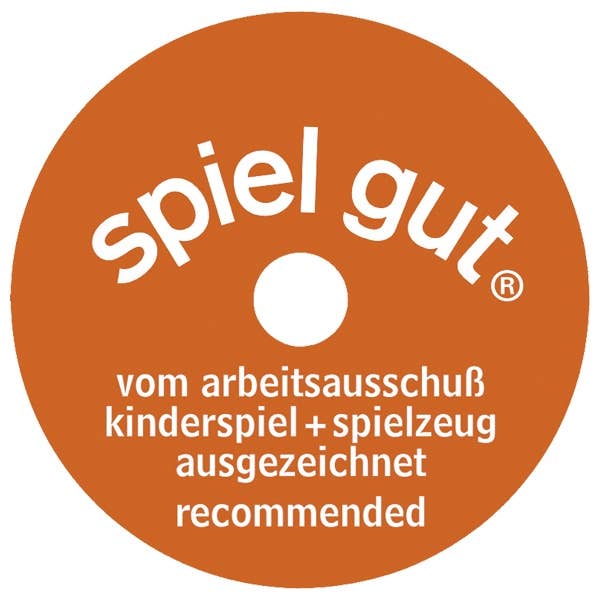 A round orange "spiel gut" label, with white text and a small center hole, is often found on handcrafted wood toys like the Holztiger Piglet (ships in one week), signifying recommendation by the arbeitsausschuß kinderspiel + spielzeug.