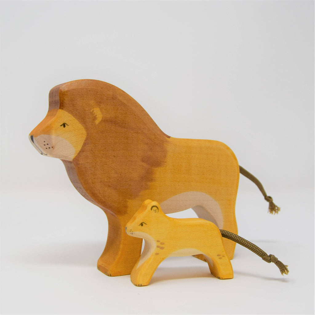 Two Handmade Wooden Lions, one large (adult) and one small (cub), stand side by side on a white background. Crafted from sustainable hardwood with simple painted details and string tails.