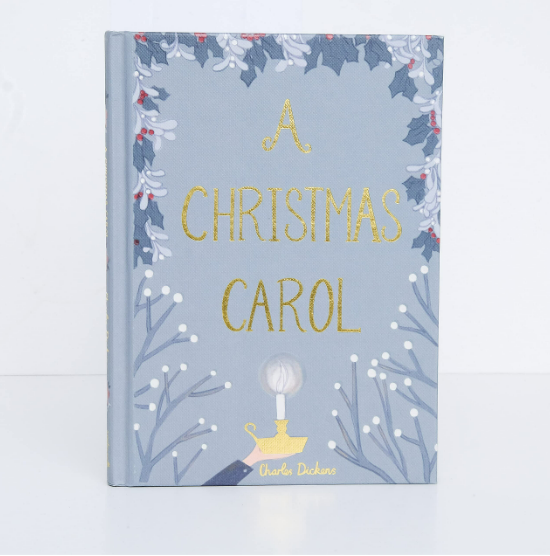 The "A Christmas Carol | Collector's Edition| Hardcover Book" features gold lettering, winter branches, holly, and a glowing lamp—inviting you into Ebenezer Scrooge’s world—on a light grey-blue cover.