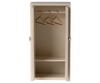 The Maileg After School Set includes a small, open wooden closet in light beige with two shelves and a hanging rod. Gold hangers enhance its minimalistic design, making it perfect for any Mouse hole Farmhouse setting.