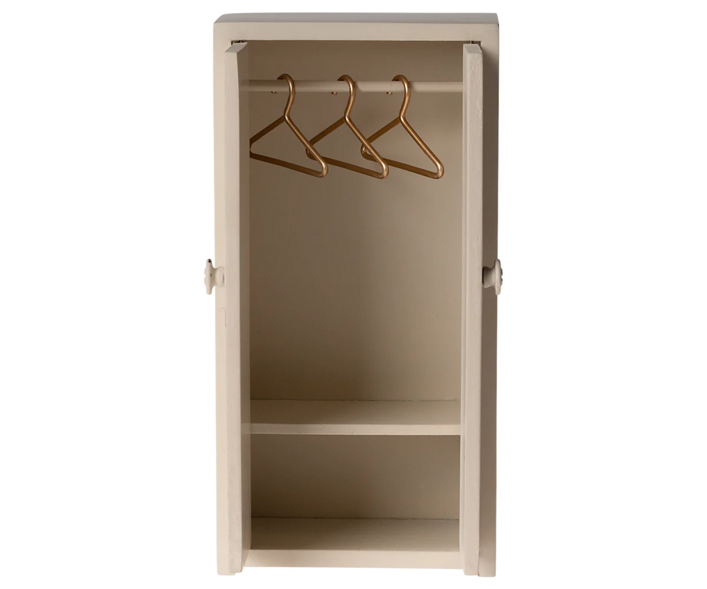 The Maileg After School Set includes a small, open wooden closet in light beige with two shelves and a hanging rod. Gold hangers enhance its minimalistic design, making it perfect for any Mouse hole Farmhouse setting.