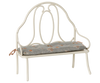 The Maileg Vintage Bench, Miniature - Off White features a decorative rounded backrest and a blue-gray floral cushion tied to the frame. Perfectly sized for bunny and rabbit spaces, it adds vintage charm and comfort to any mini setting.