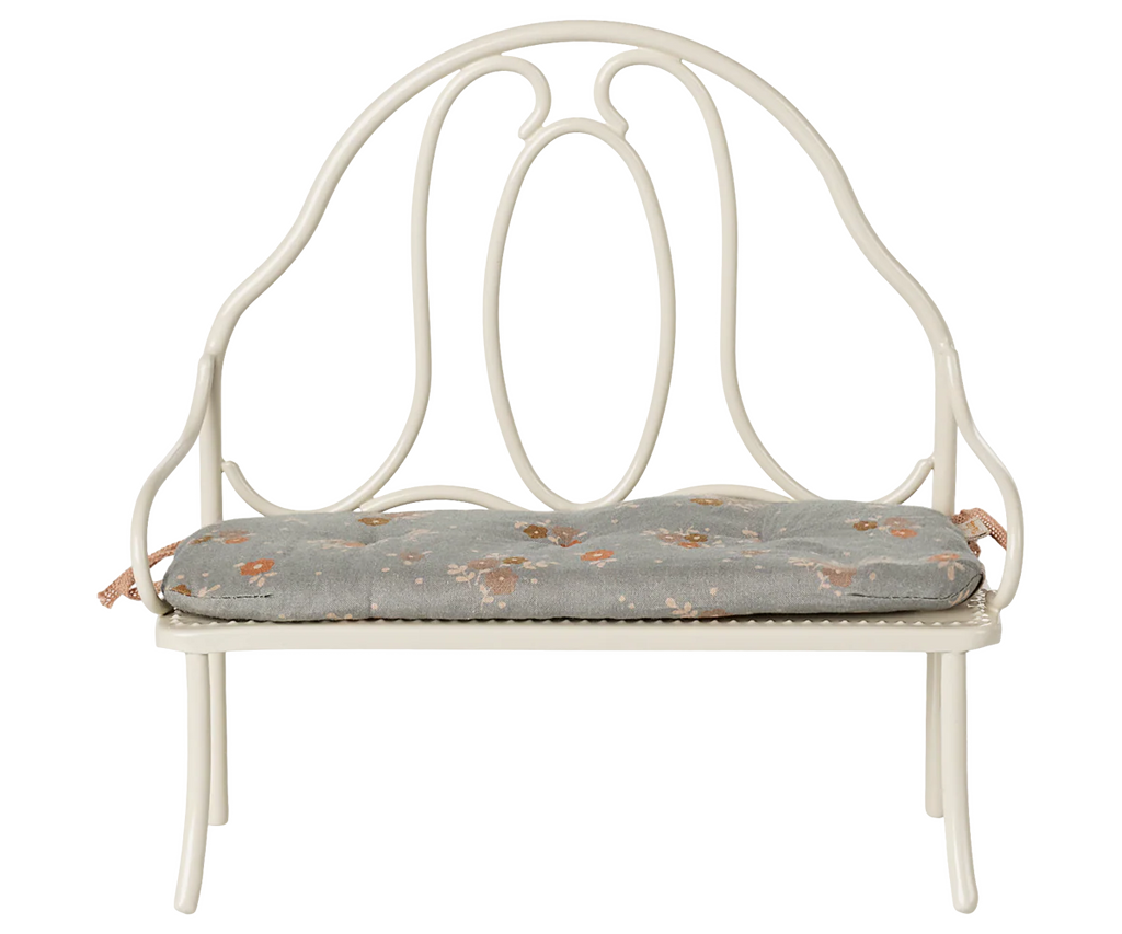 The Maileg Vintage Bench, Miniature - Off White features a decorative rounded backrest and a light gray floral cushion, creating a cozy, perfectly sized seat for bunny and rabbit friends.