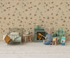 A cozy miniature Mouse hole Farmhouse scene features a bed, nightstand, clock, table, fireplace, and the Maileg Folding Chair, Mouse - Green Checker. A Maileg mouse toy in a striped shirt sits by the fire with tiny food; animal wallpaper adds charm.