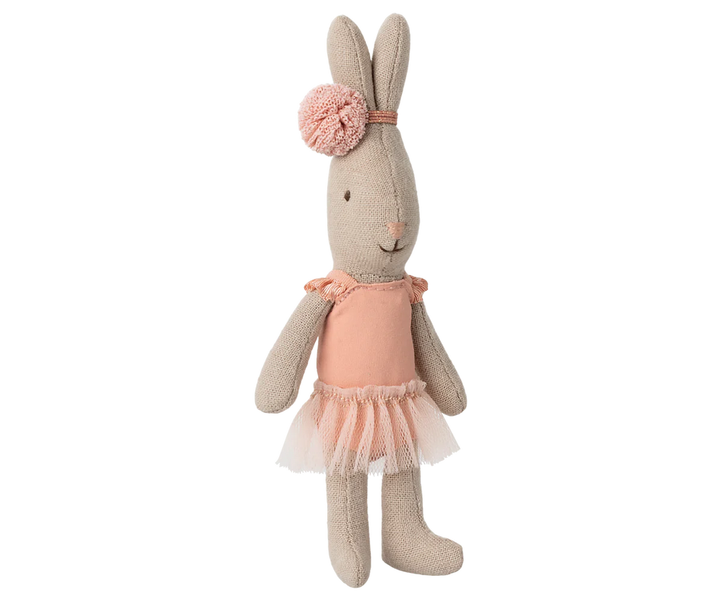 A Maileg Rabbit, Micro wears a rose ballet suit and skirt, standing upright like a tiny dancer against a blurred striped background.