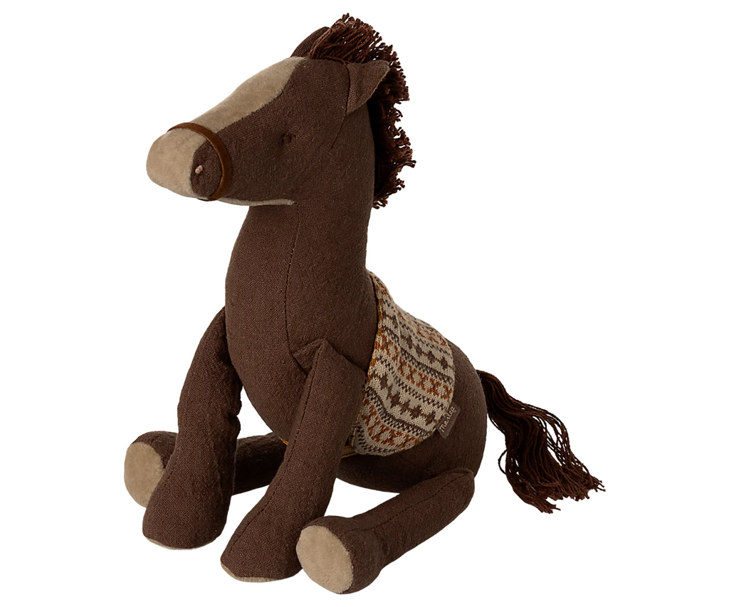 The Maileg Pony, Medium is a brown plush toy with a patterned saddle, light brown snout, and yarn mane and tail. Made of soft fabric, it sits upright for charming display or cuddling.