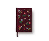 The Gracie Mini Embroidered Journal in burgundy features colorful floral and leaf embroidery, blank unlined pages, and a matching ribbon bookmark, displayed against a white background.