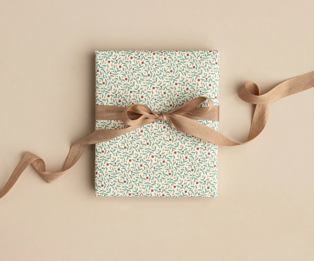 A rectangular gift wrapped in pale floral paper, tied with Maileg Ribbon - Soft Brown (10m) in a bow, sits on a beige background.