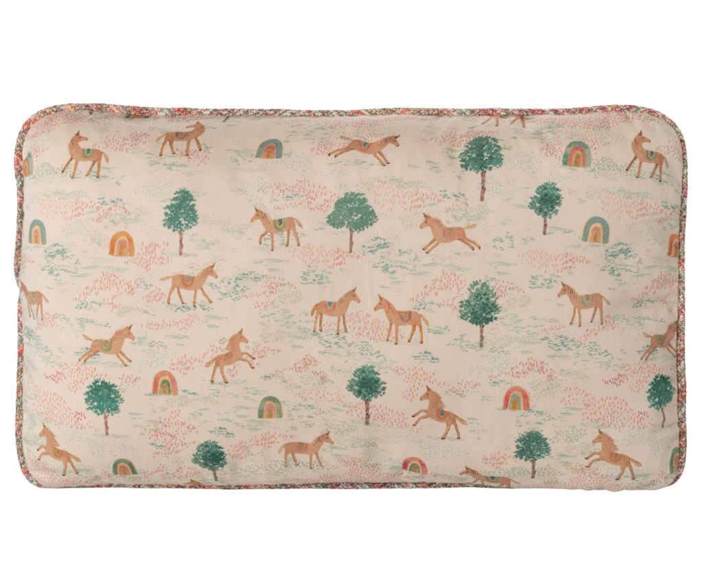 The Maileg Cushion - Unicorn is a rectangular cotton cushion with a whimsical unicorn, green trees, and rainbow pattern on a cream background, finished with floral trim and crafted from quality printed fabrics.