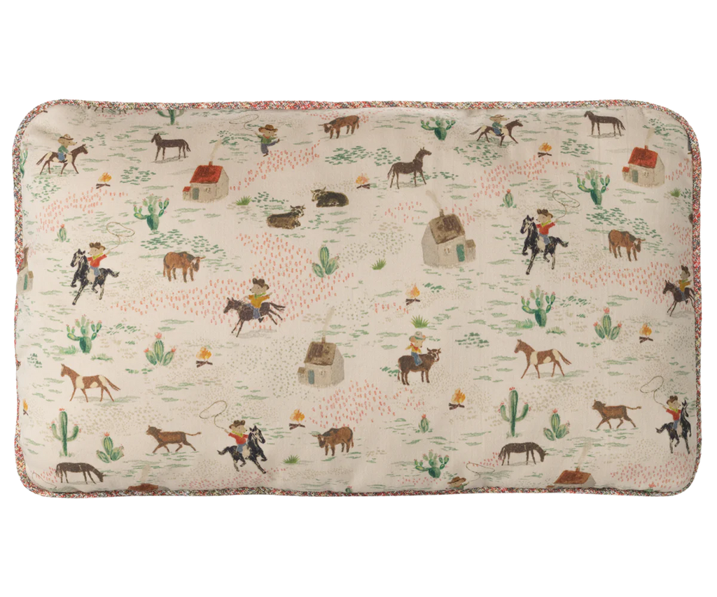 The Maileg Cushion - Pony features a cream background made from 100% cotton and is decorated with playful Western-themed prints—cowboys, cattle, cacti, houses, and desert plants—ideal for fans of printed fabrics.