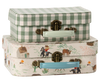 Two small decorative suitcases from the Maileg Cowboy Set are stacked: the top has a green and white gingham pattern with a mint handle, and the bottom shows a farm and cowboy print with a blue handle. Both feature metal clasps.