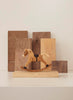 A small wooden rocking horse toy is displayed on a light surface, with upright wooden planks in the background—part of our Newborn Gift Set.