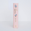 The spine of the light pink hardcover "Emma | Collector's Edition" stands upright, featuring gold foil lettering and blue flower illustrations, set against a white background.