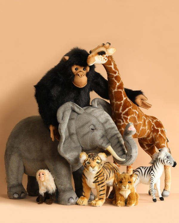 The Great Safari Expedition Set features plush toy animals—a Ride-On Elephant, chimpanzee, giraffe, monkey, tiger, lion cub, and zebra with realistic details—arranged together against a light beige background.