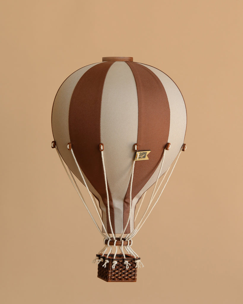 The Hot Air Balloon - Dark Brown features brown and beige stripes with a small woven basket, set against a solid light brown background—ideal for handmade children's room decoration or whimsical hot air balloon-themed decor.
