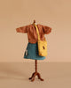 A Maileg Extra Clothing set for Mum Mouse is displayed: an orange striped top, blue plaid skirt, and yellow bag are shown against a beige background.