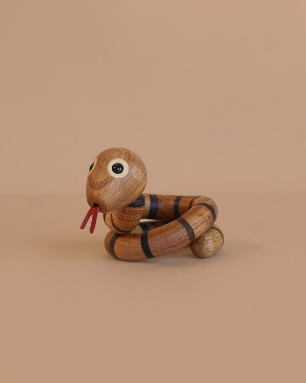 Spring Copenhagen The Snake is a wooden décor piece with big round eyes, black stripes, and a red tongue, coiled on beige—perfect as a spiritual gift or for celebrating the Chinese zodiac snake.