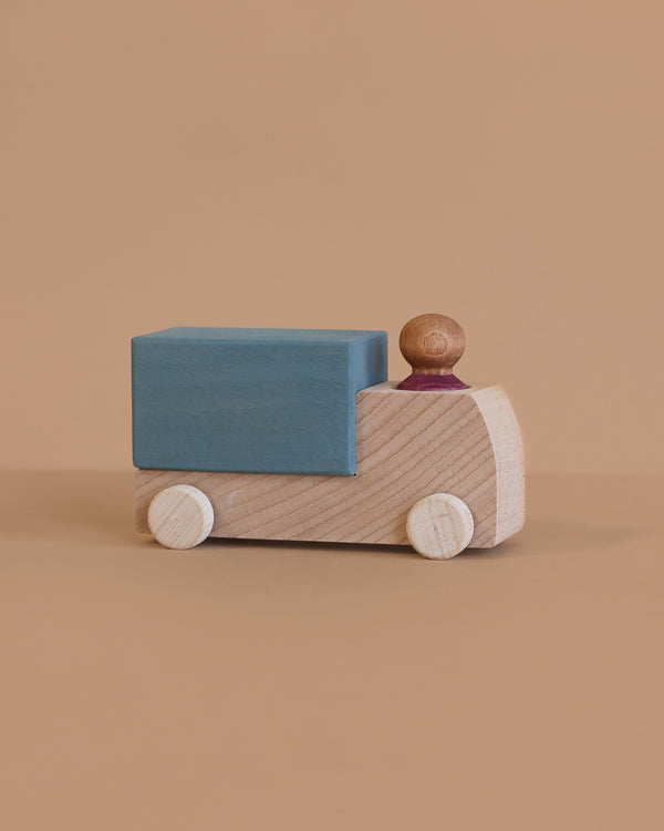 The Lubulona Wooden Truck - Grey features a minimalist wooden design with a grey finish, includes a blue rectangular block as cargo and a small wooden driver, making it an eco-friendly and timeless toy for imaginative play.