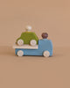 The Lubulona Wooden Tow Truck - Grey carries a green toy car with two peg people, perfect for small-world play, displayed on a plain beige background.