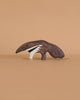 The Holztiger Anteater, a handcrafted wooden toy, features a painted anteater design and sits on a light brown surface with a beige background, showcasing the quality of Holztiger figures made in Europe.