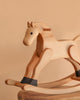 The Spring Copenhagen Wooden Rocking Horse – Final Sale features a natural finish and minimalist Nordic design, displayed on a wooden surface with a beige background for an elegant look.
