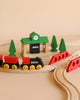 The BRIO World Train Set Classic Figure 8 Set features classic red and black trains on curved tracks, with red bridges, green pine trees, and a green station—crafted in timeless Scandinavian design.