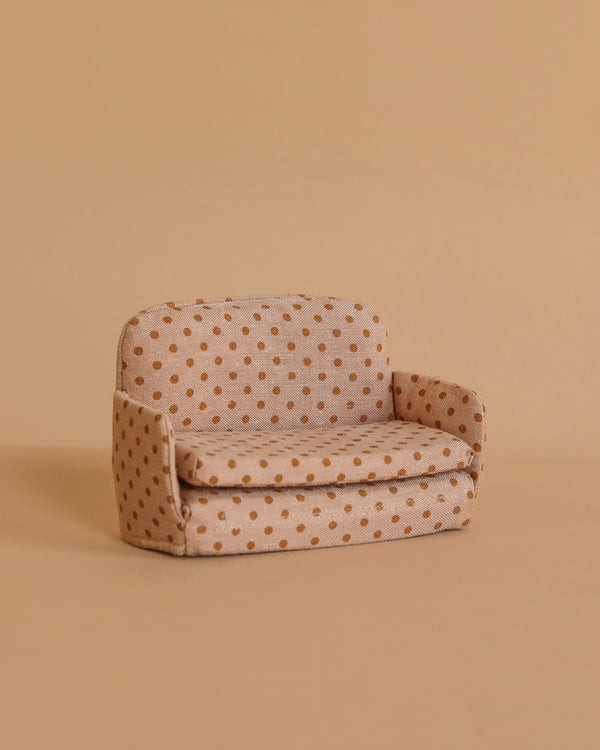 The Maileg Sofa Bed, Mouse - Dots features brown polka dots on a small beige frame, set against a plain light brown background—perfect for bringing charm to your SuitCasa living room scene.