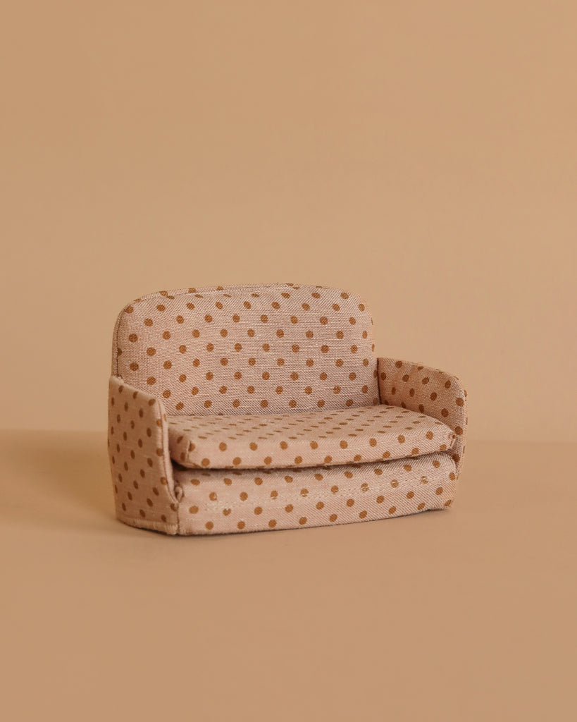 The Maileg Sofa Bed, Mouse - Dots features brown polka dots on a small beige frame, set against a plain light brown background—perfect for bringing charm to your SuitCasa living room scene.
