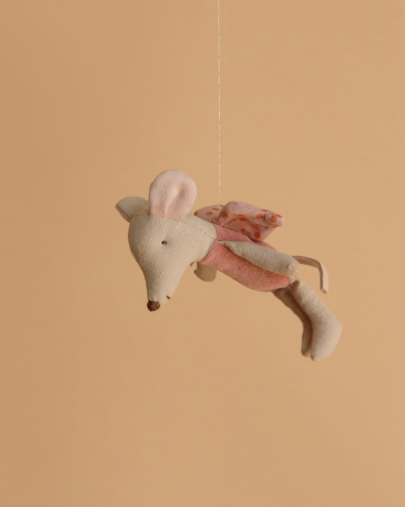 The Maileg Fairy Mouse, Little - Rose features soft wings and large ears, suspended by a thin string to inspire imaginative play against a plain beige background.