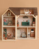 The Maileg Fully Furnished Farmhouse features six detailed rooms with miniature furniture and plants. Patterned wallpaper and a Maileg mouse doll in an armchair create a cozy, inviting dollhouse atmosphere.