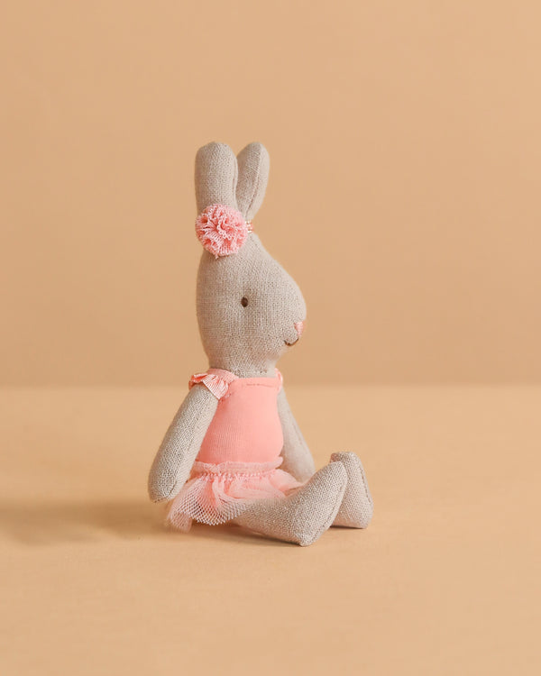 A Maileg Rabbit, Micro - Ballet Suit And Skirt, Rose sits against a beige background, dressed in a rose ballet suit and skirt with a matching headband.