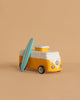 The VW Beach Bus Sunset is a small yellow and white Volkswagen Type 2 toy van with a surfboard leaning against its side, shown on a plain beige background.