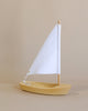 The Handmade Wooden Sailboat, crafted from lime wood with a white triangular sail, stands upright on a beige background—ideal for children aged 3 and up.