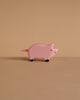 The Holztiger Piglet is a small, pink, handcrafted wooden toy with black feet, displayed on a beige surface against a matching background and exemplifying Holztiger’s renowned quality.