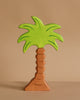 The Holztiger Palm Tree is a handcrafted wooden figure featuring a brown trunk and bright green leaves, shown standing upright against a plain beige background.