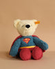The Steiff Superman Teddy Bear, 12 Inches, features a plush bear in a blue and red Superman costume with cape and "S" logo, sitting upright against a beige background—perfect for superhero adventures.