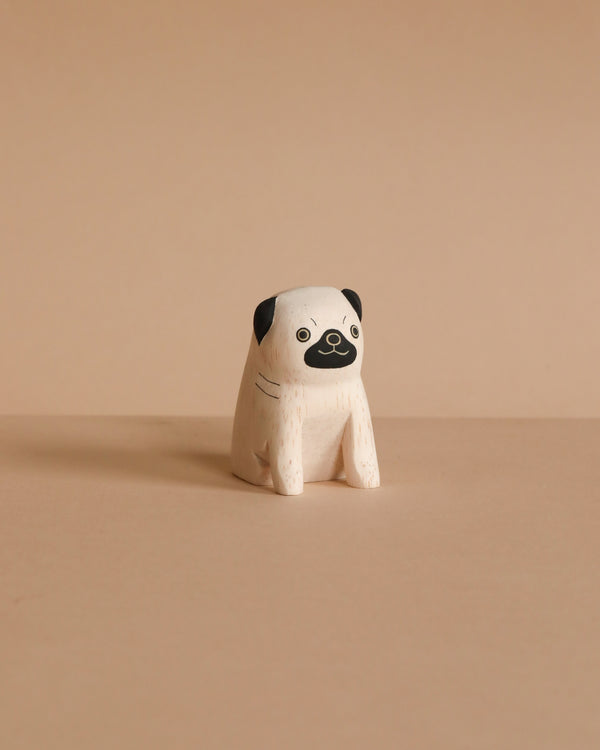 The Handmade Tiny Wooden Animals - Pug Dog is a minimalist, small handcrafted figurine made from Albizia wood, featuring a white body and hand-painted black face details, showcased on a plain beige background.
