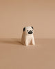 The Handmade Tiny Wooden Animals - Pug Dog is a minimalist, small handcrafted figurine made from Albizia wood, featuring a white body and hand-painted black face details, showcased on a plain beige background.