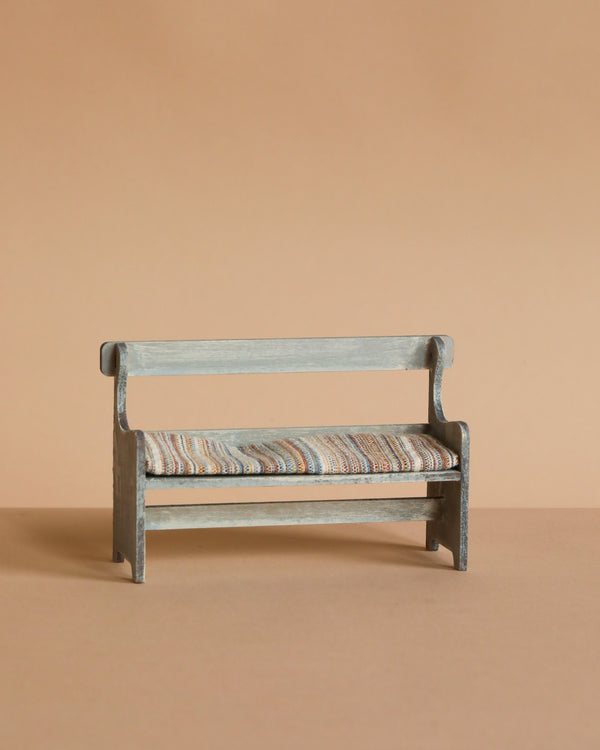 The Maileg Mouse Bench - Off-White is a charming small wooden bench with a striped cushioned seat, set against a solid light brown background—perfect for dollhouse enthusiasts and mouse families alike.