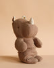 The Maileg Small Rhino - Chocolate, crafted from soft fabric and recycled polyester, sits upright on a neutral beige background—perfect for joining your Safari friends collection.