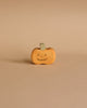 The Wooden Happy Jack-O-Lantern, a small, orange wooden pumpkin crafted from sustainable hardwood with a green stem and a carved smiling face, stands on a beige background. Its simple design gives it a cute and minimalist Halloween appearance, reminiscent of a classic Jack-O-Lantern.