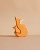 The Handmade Wooden Snuggling Foxes set features two minimalistic fox figurines, one large and one small, hand crafted from sustainable hardwood and finished with natural, non-toxic stains against a beige background.